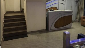 A reception area with a modern desk, a staircase, and a fan on the wall. - Hotel Nagpal (Haridwar)