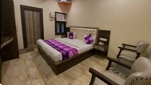 A bedroom with a bed, nightstand, chair, and a desk. - Hotel Nagpal (Haridwar)