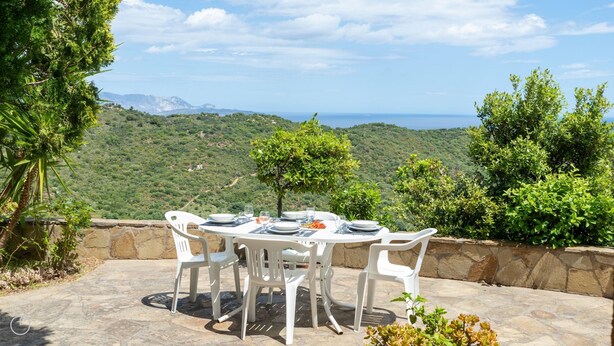 A table set outdoors with a scenic view of hills and the sea. - La Casa di Margherita (Budoni)