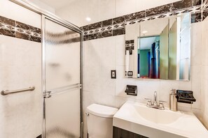 Ein modernes Badezimmer mit Duschkabine aus Glas, einer weißen Toilette und einem Waschbecken mit Spiegel darüber.