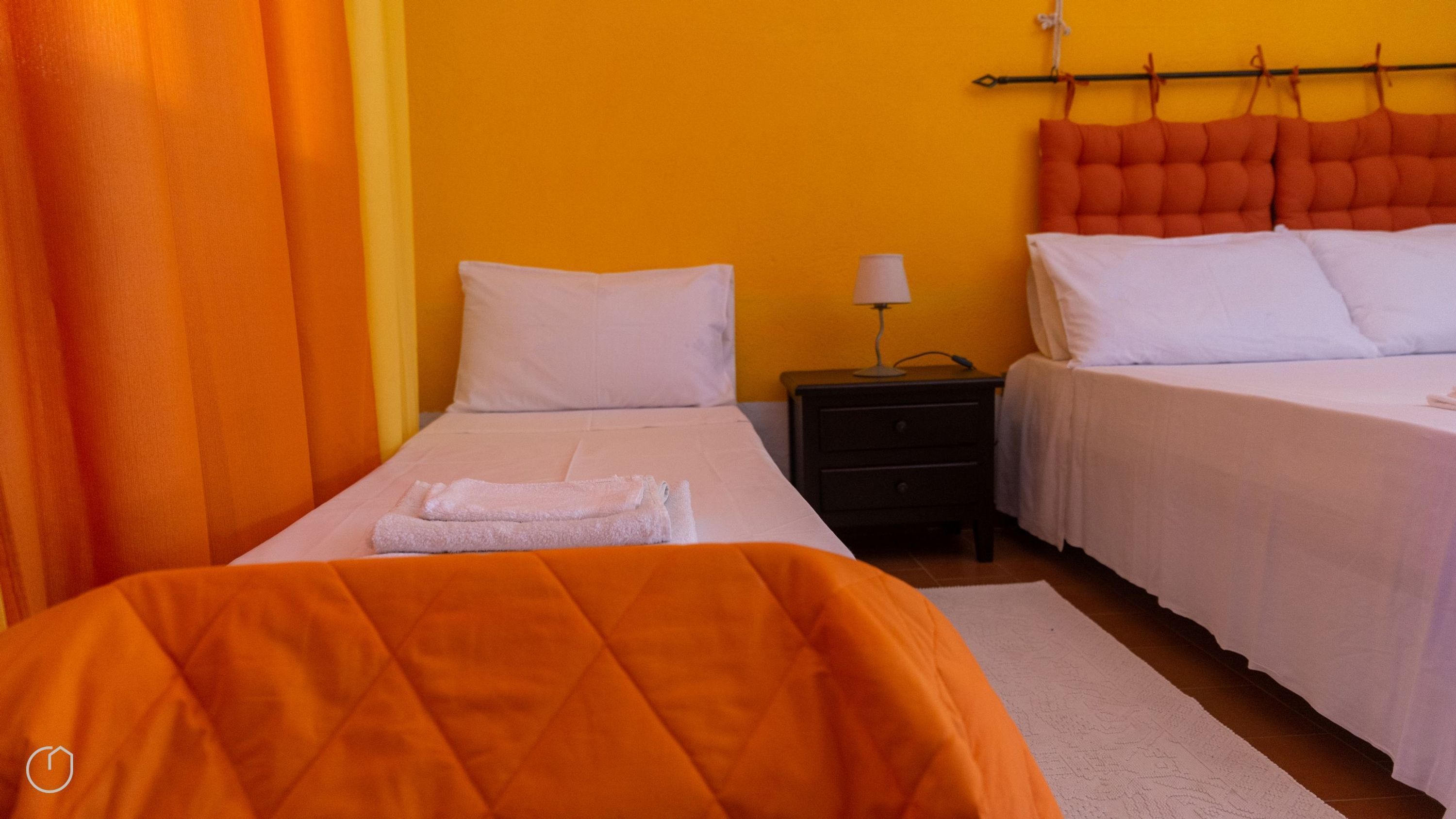 Habitación de hotel con dos camas, una mesita de noche y una ventana con cortinas.
