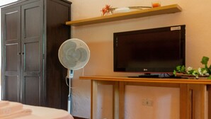 A room with a dark wooden wardrobe, a flat-screen TV on a wooden stand, and a wall-mounted fan. - La Casa di Elisabetta (Budoni)