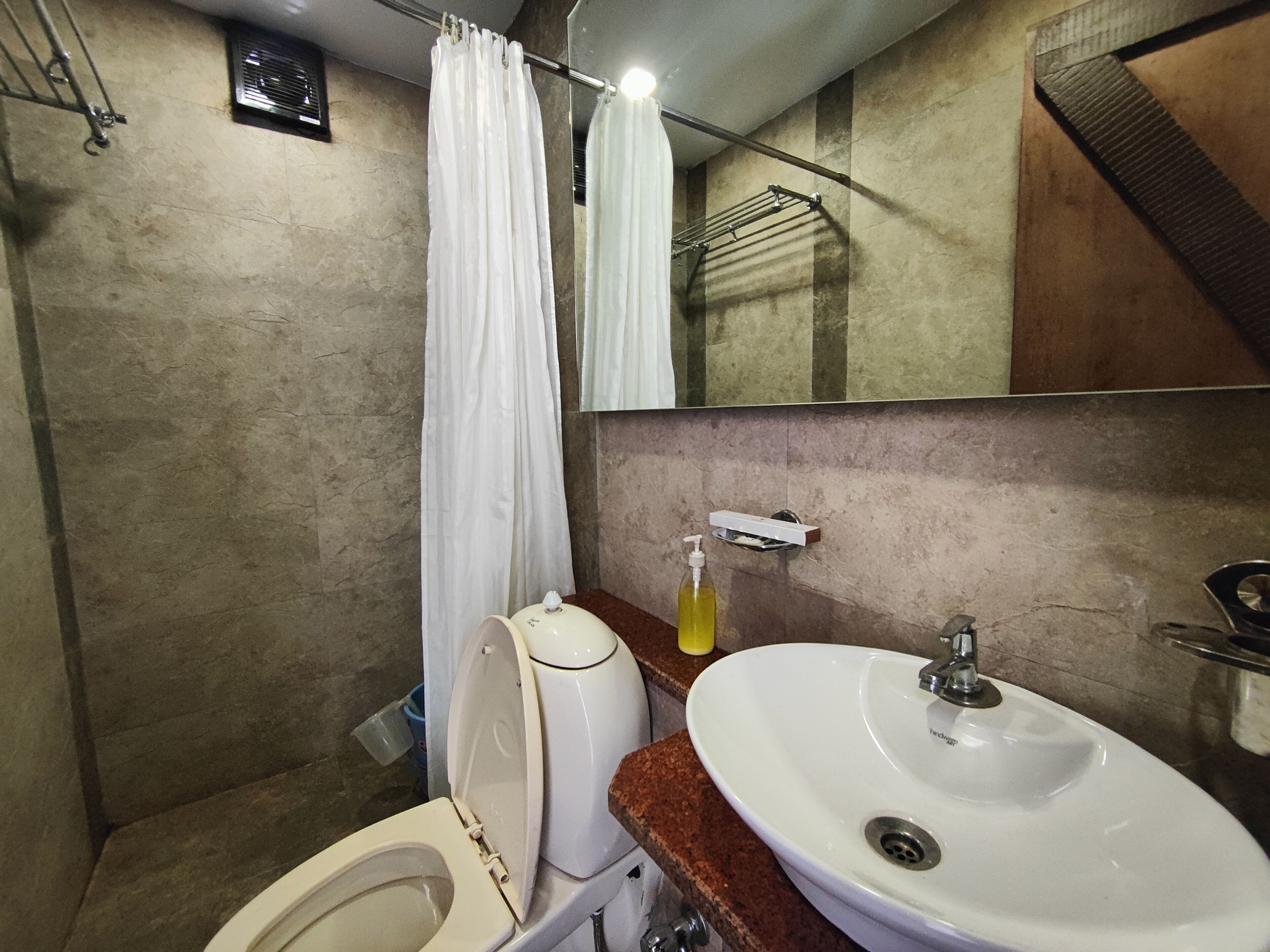 A bathroom with a toilet, sink, and shower curtain.