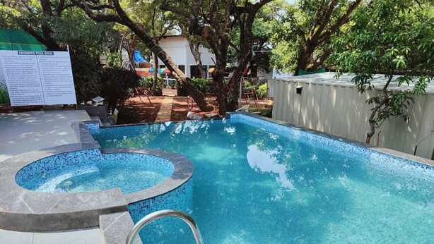 A swimming pool with a hot tub, surrounded by trees and a sign with rules. - Rain Raga Resort (Mahabaleshwar)