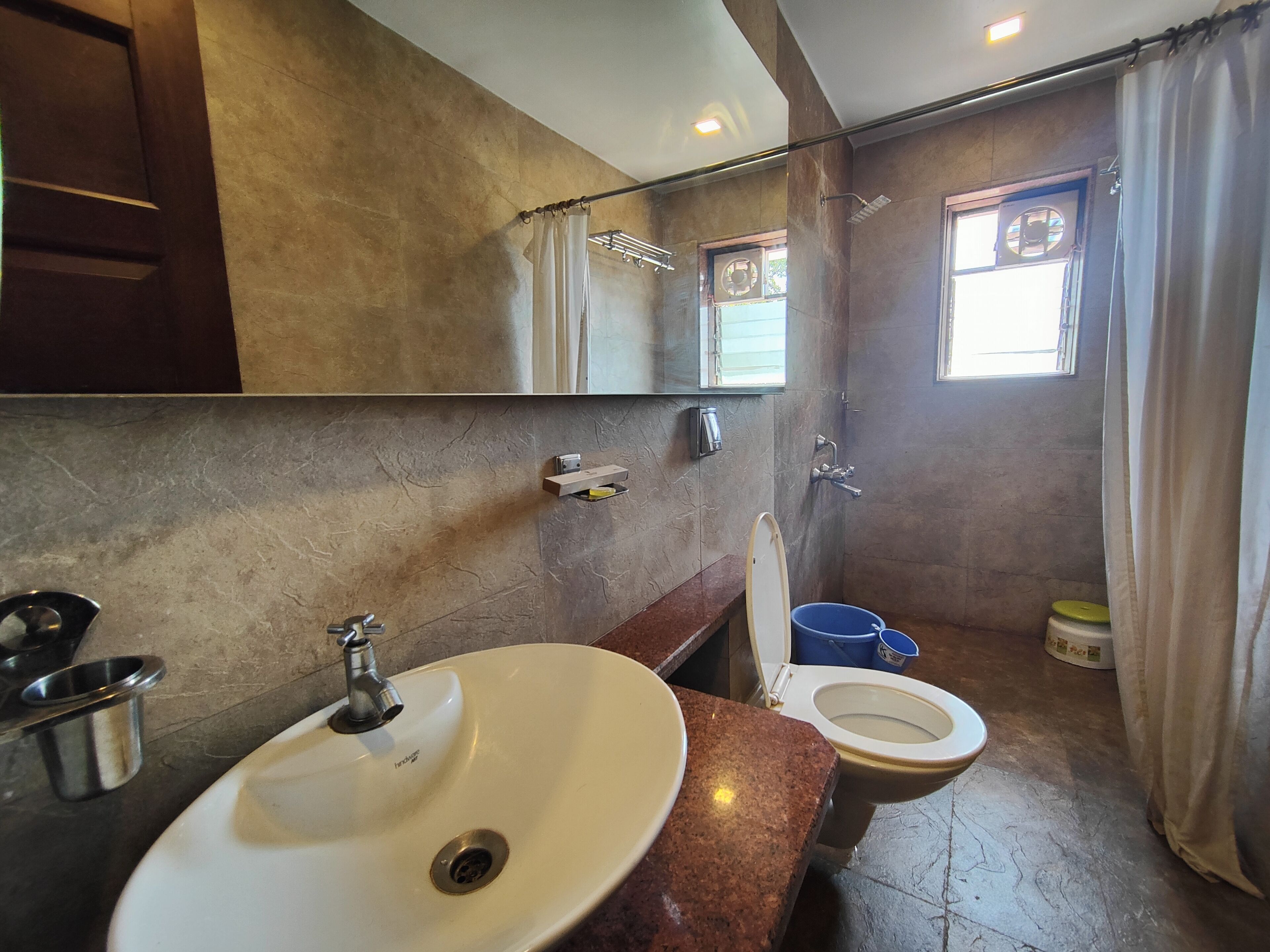 A bathroom with a white sink, a toilet, a mirror, and a shower area.