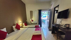 A hotel room with two beds, a TV, a desk with a kettle, and a balcony with a view. - Rain Raga Resort (Mahabaleshwar)