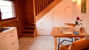 A wooden cabin interior with a kitchen, dining area, and staircase. - Neizhig Koad Petit Nid en Bois (Péaule)