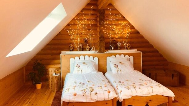 A cozy attic bedroom with two beds, wooden walls, a skylight, and string lights. - Neizhig Koad Petit Nid en Bois (Péaule)