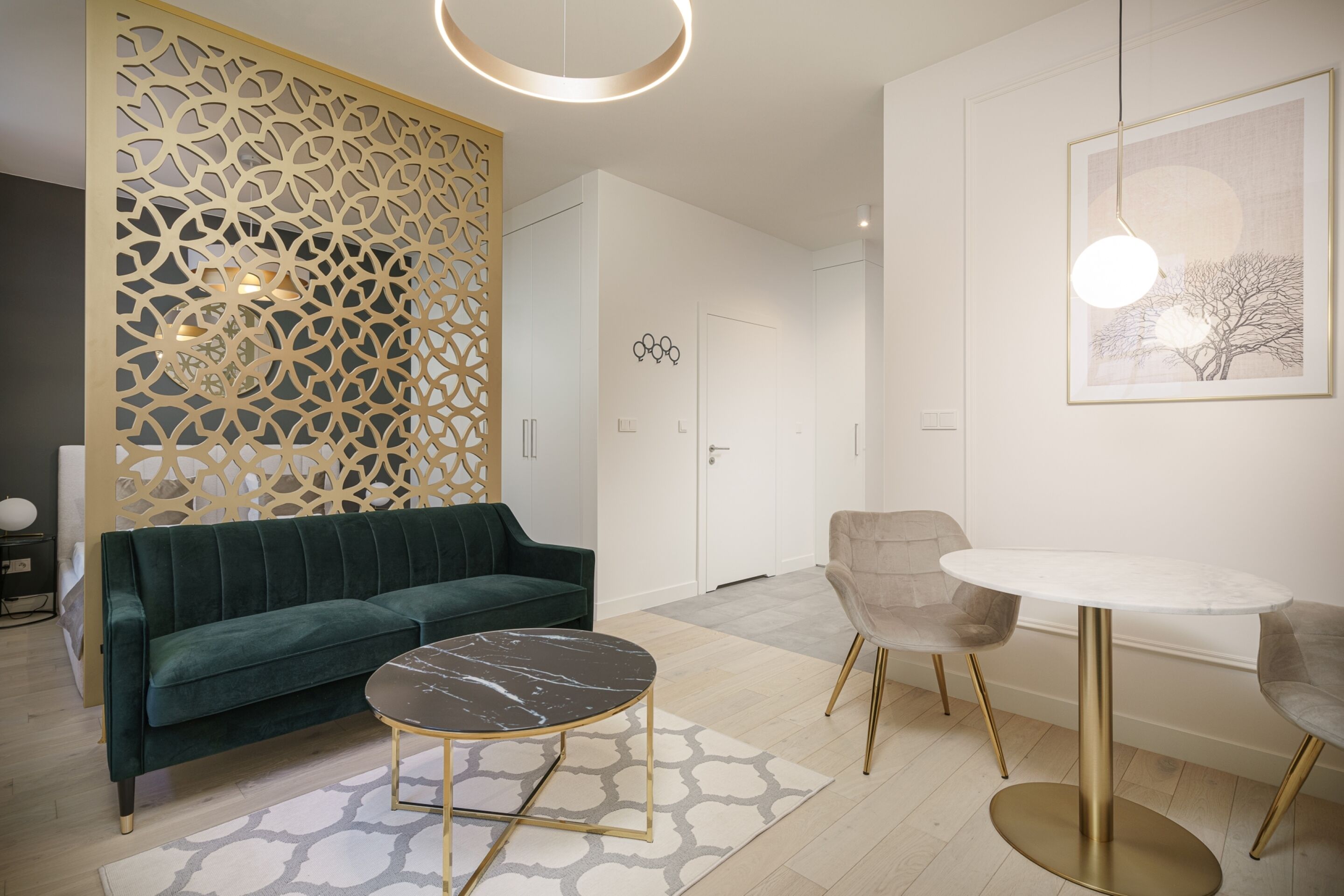 A modern living room with a green sofa, a marble coffee table, and a round table with chairs.