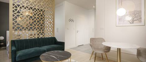 A modern living room with a green sofa, a marble coffee table, and a round table with chairs.