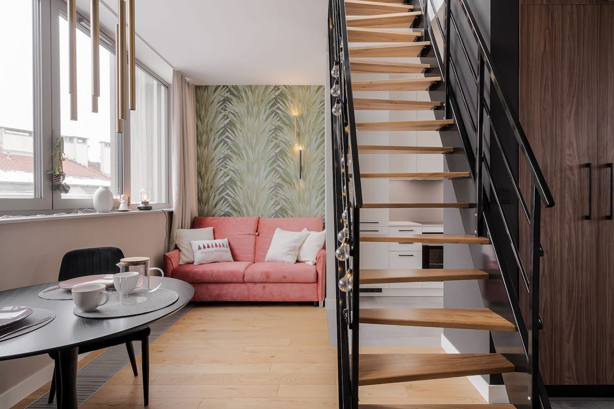 Um interior moderno com escada, sofá rosa e área de refeições.