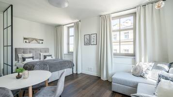 Una habitación moderna y bien iluminada con una cama, un sofá, una mesa de comedor y una planta pequeña.