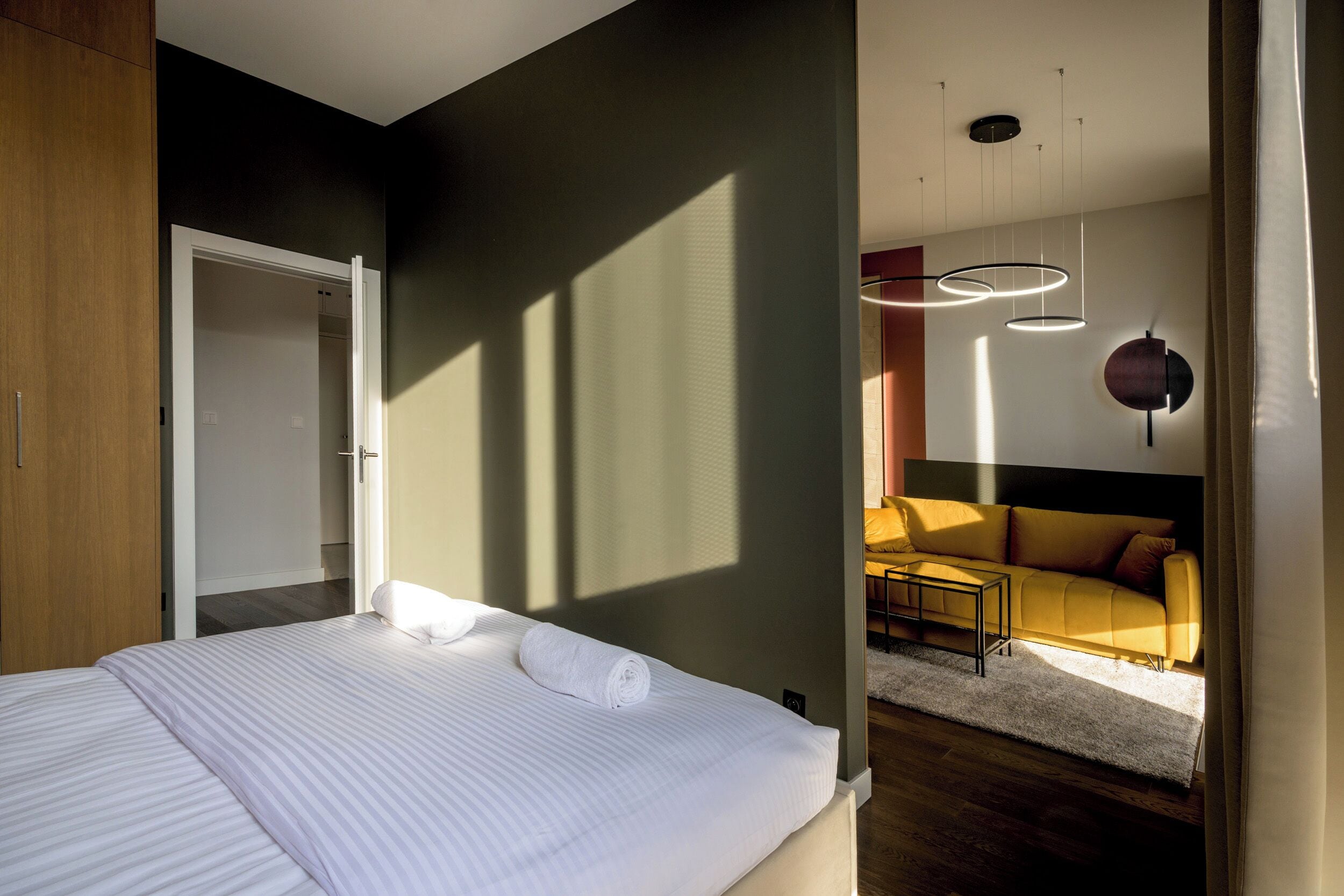 Un dormitorio moderno con una cama grande, un armario de madera y un sofá en la zona de estar contigua.