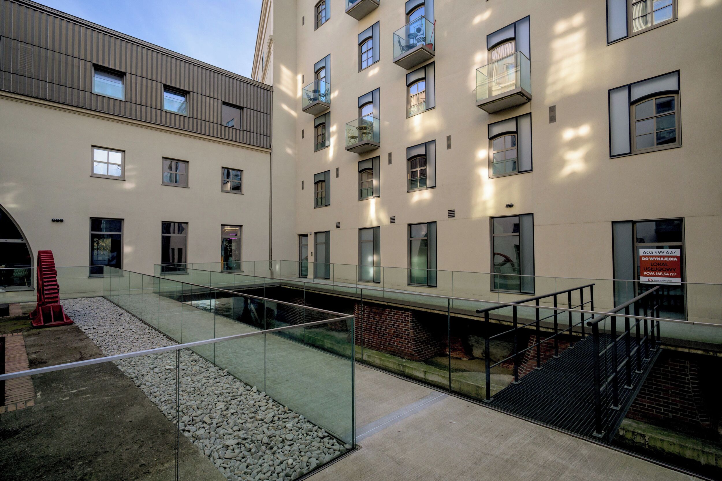 A modern building with multiple floors, balconies, and a glass walkway.