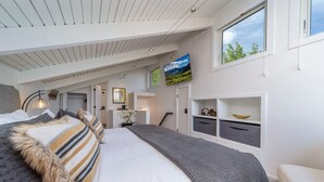 A modern bedroom with a large bed, a TV mounted on the wall, and built-in storage units. - Beautifully Renovated 3BR, 3BA w Pool & Hot Tub (Snowmass Village)