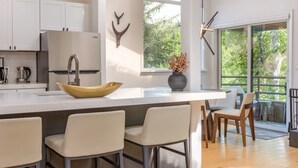 A modern kitchen with a large island, white cabinetry, and a view of greenery outside. - Beautifully Renovated 3BR, 3BA w Pool & Hot Tub (Snowmass Village)