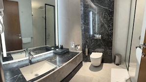 Une salle de bain moderne avec un grand miroir, deux lavabos, des toilettes et une douche.
