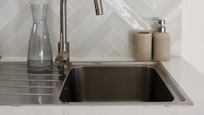 A kitchen with a stainless steel sink, a glass vase, and a soap dispenser.