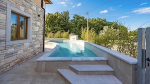 A swimming pool with steps leading up to it, surrounded by stone walls and greenery. - Casa Dika Pool & Lounge (Marcana)