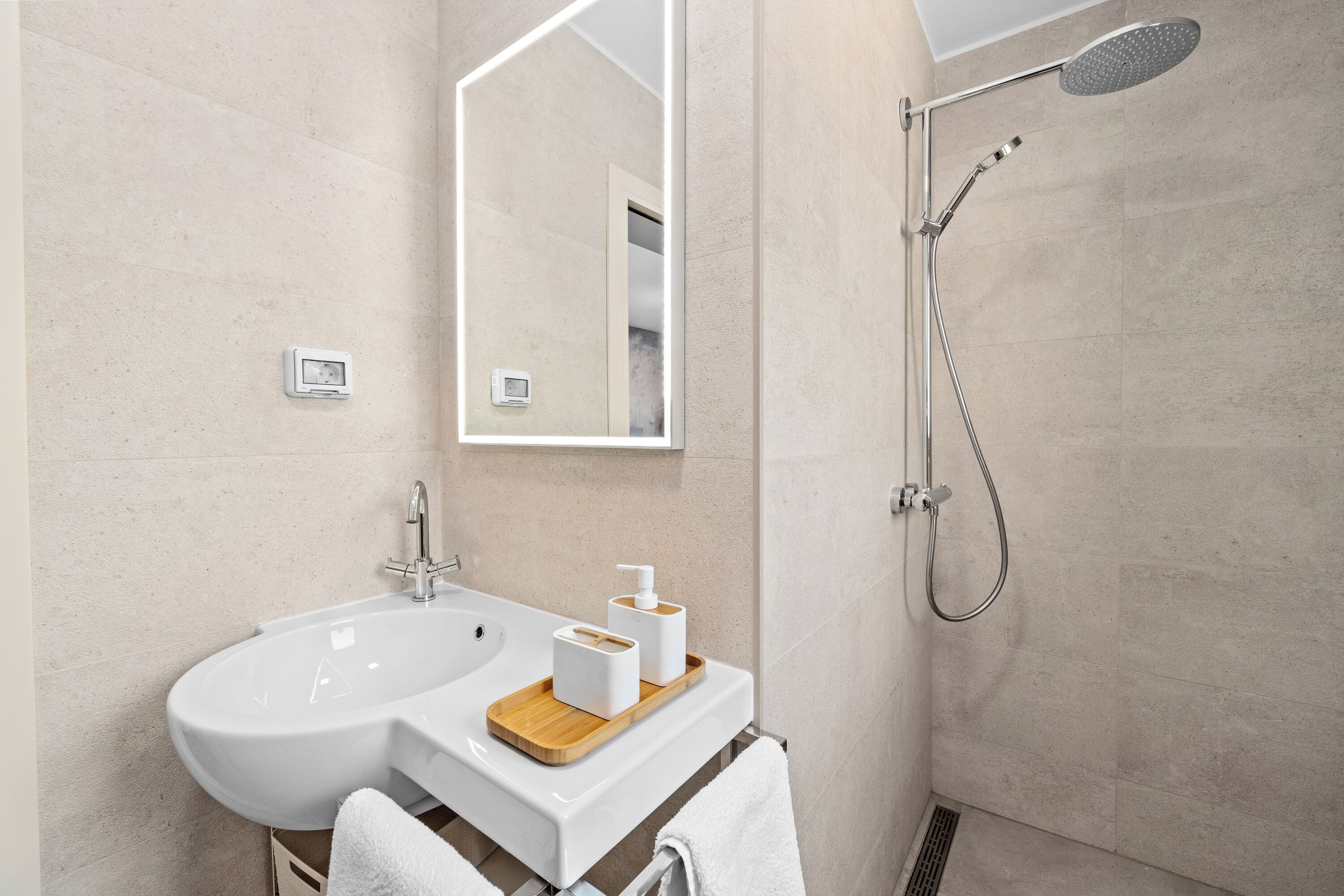 Ein Badezimmer mit Waschbecken, Spiegel, Dusche und Handtuchhalter.