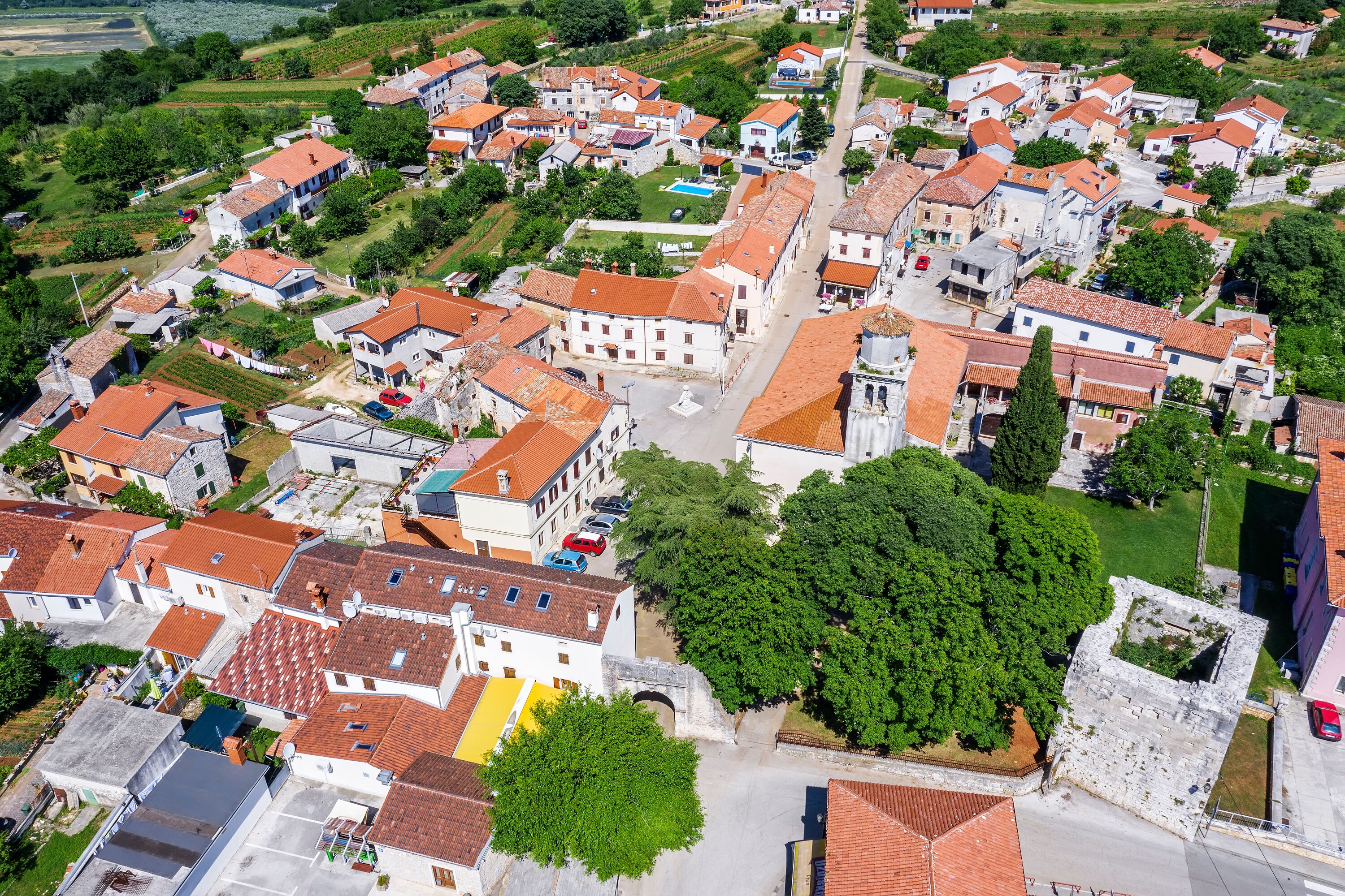 Vue aérienne d’un village avec des bâtiments traditionnels, des rues étroites et des espaces verts.