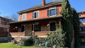Una casa de dos pisos con fachada roja, techo de tejas y un pequeño balcón.