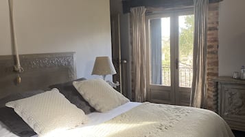 Een slaapkamer met een bed, een lamp, een deur en uitzicht op de omgeving.