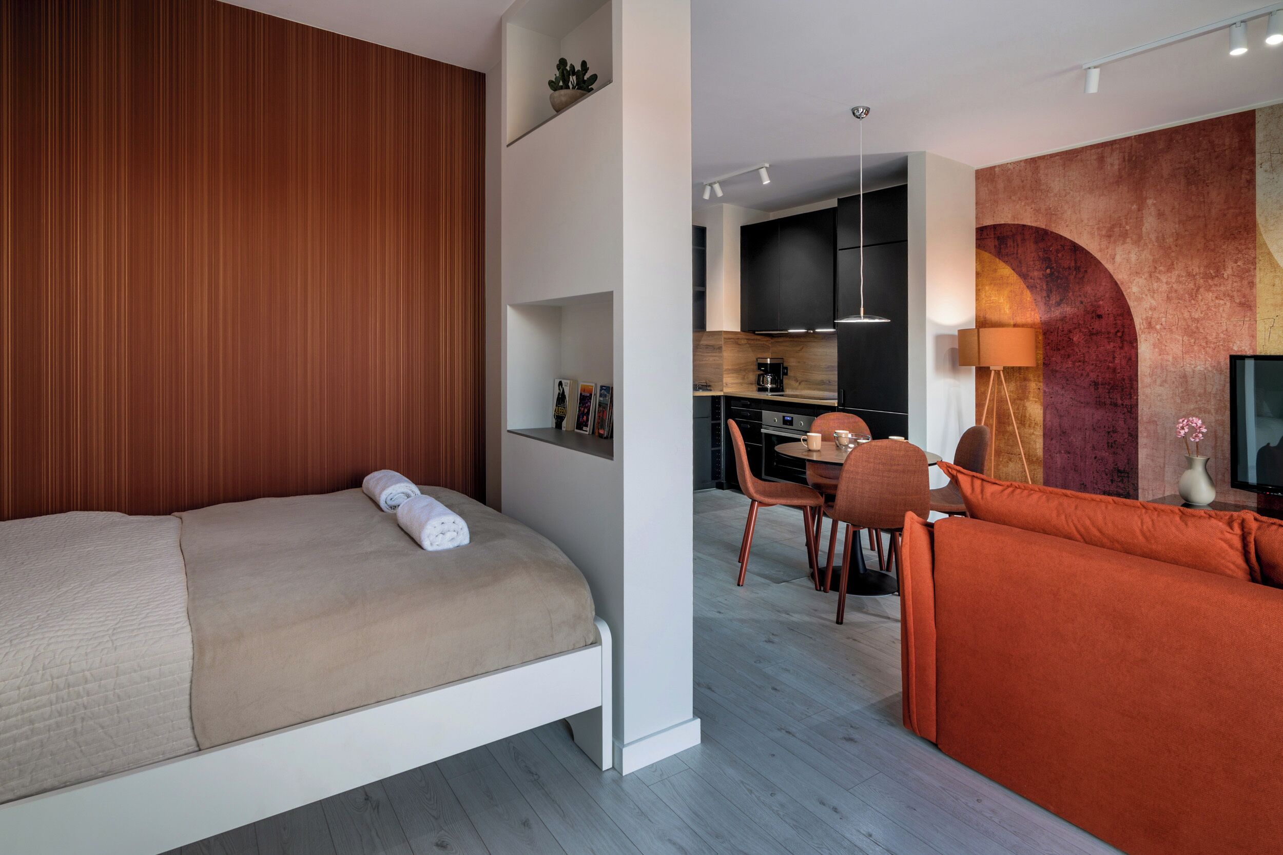 Ein modernes Hotelzimmer mit Bett, Sofa, Essbereich und einer Küche.