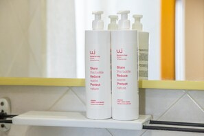 Dos botellas de jabón orgánico para manos y cuerpo sobre un estante blanco en un baño.