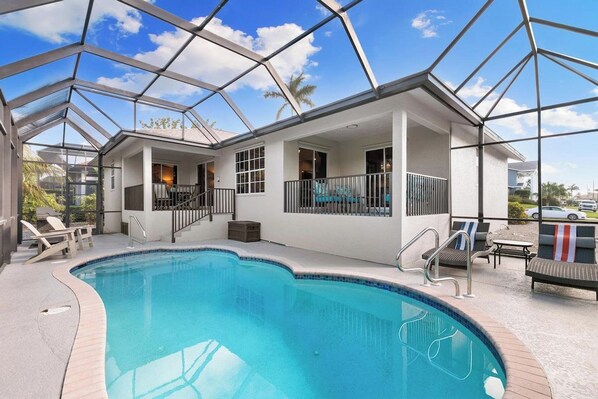 A swimming pool with a glass ceiling, lounge chairs, and a covered patio area.