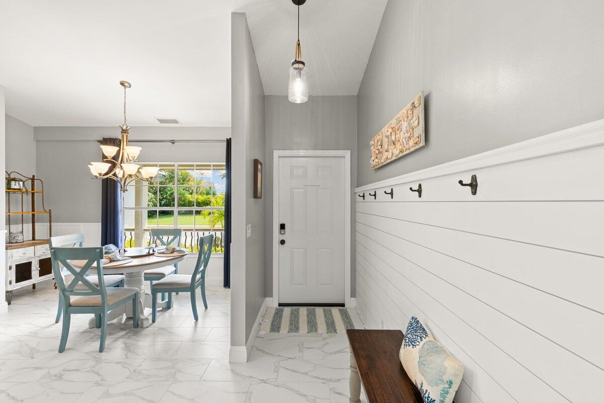 A hallway with a white door, a bench, and a wall-mounted coat rack.