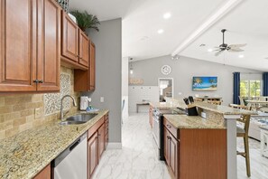 A kitchen with granite countertops, wooden cabinets, and a central island.
