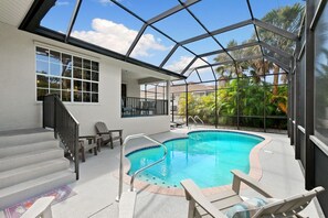 Una piscina interior con techo de cristal, rodeada por una terraza con sillas y una escalera.