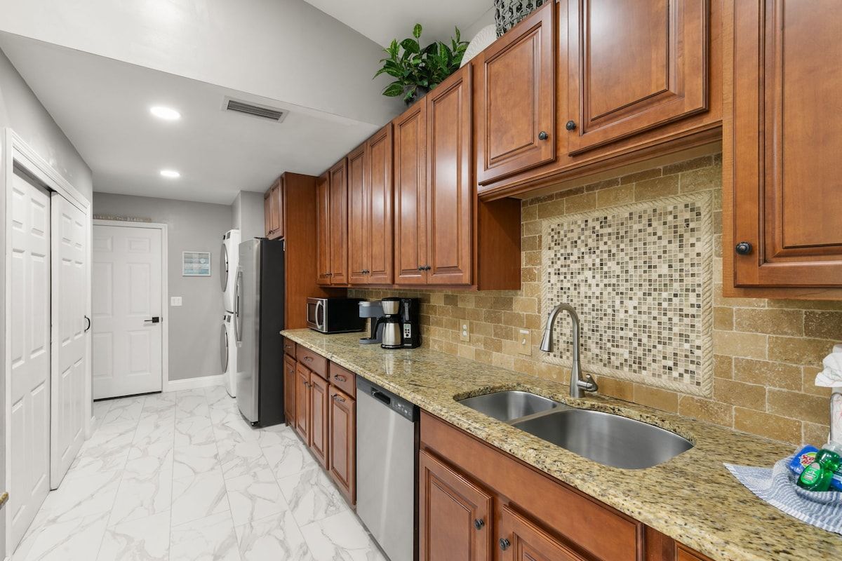 A kitchen with wooden cabinets, a granite countertop, a sink, and a tiled backsplash.