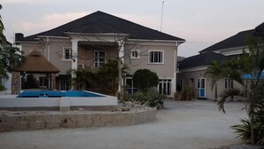 A residential area with a large house featuring a swimming pool, a covered patio, and a well-maintained garden. - Captivating 3-bed Apartment in Lagos (Lekki)