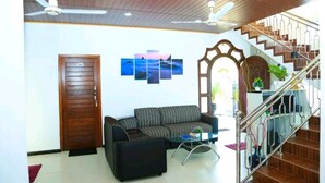 A living room with a sofa, a coffee table, and a staircase with a railing. - Blue Diamond Resort (Trincomalee)