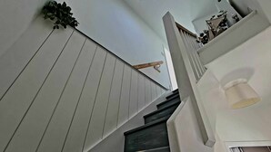 Eine Treppe mit weißen und dunkelholzfarbenen Stufen, einem Geländer und einer Lampenleuchte auf der rechten Seite.