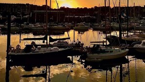 Ein Yachthafen mit vertäuten Booten im ruhigen Wasser bei Sonnenuntergang.
