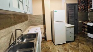 Una cocina compacta con un lavabo, un refrigerador blanco y una estufa.