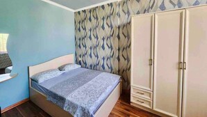 Un dormitorio con cama, armario y papel tapiz estampado.
