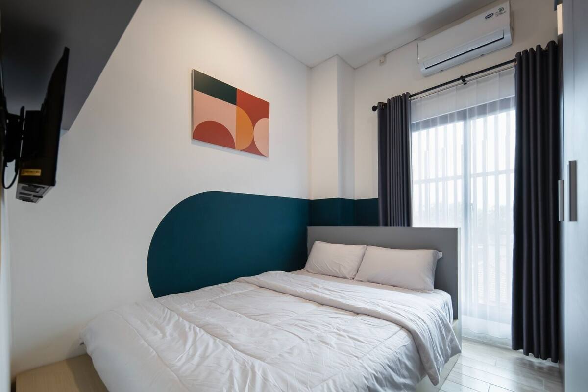 Ein modernes Hotelzimmer mit einem Bett, einem Gemälde, einer Klimaanlage und einem fenster mit Vorhängen.