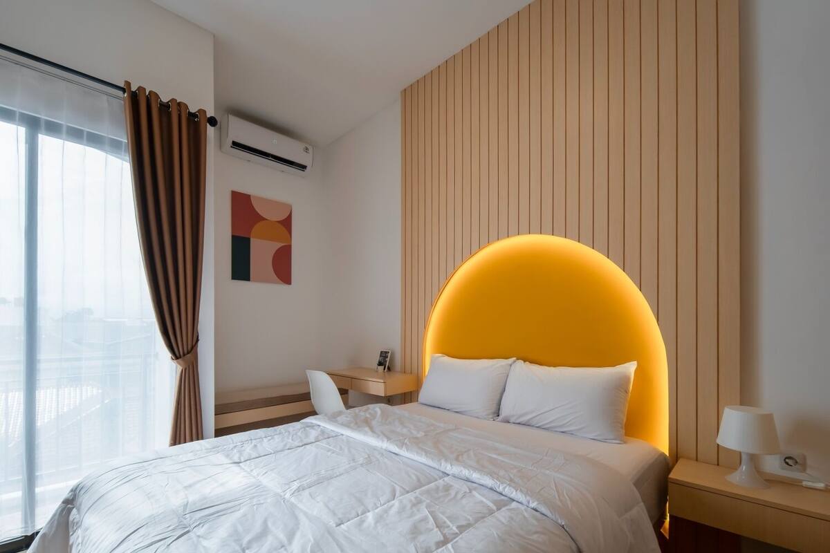 Ein modernes Hotelzimmer mit einem großen Bett, einem Schreibtisch und einem Nachttisch.