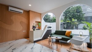 Ein moderner Empfangsbereich mit Wandverkleidung aus Holz, einer Rezeption, einem grünen Sofa, einem weißen Stuhl und einem kleinen Tisch.