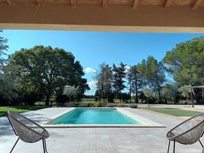 A rectangular swimming pool with two wicker chairs facing it, surrounded by a tiled patio area. - Villa 12 pers, air-conditioned, 4x10 pool, poolhouse, in the countryside but not isolated. (Orange)