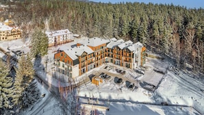 A snow-covered building complex with multiple buildings, surrounded by trees and a clear sky.