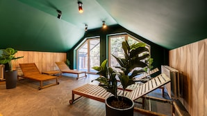 A cozy, well-lit room with wooden furniture, large windows, and potted plants.