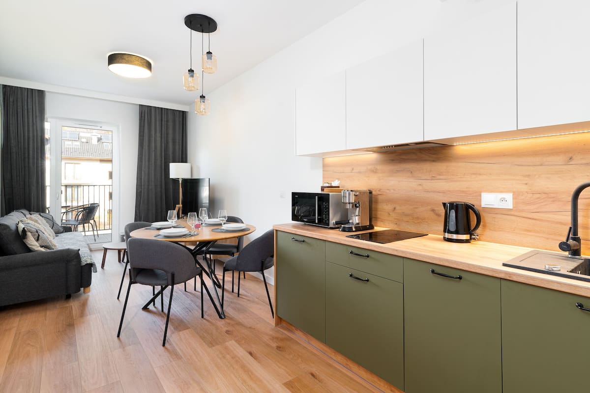A modern kitchen with a wooden countertop, a black coffee maker, and a built-in microwave.