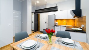 A modern kitchen with white cabinets, a black range hood, and a wooden countertop. - Apartamenty Sun & Snow Ostoja Parku Narodowego (Szklarska Poreba)