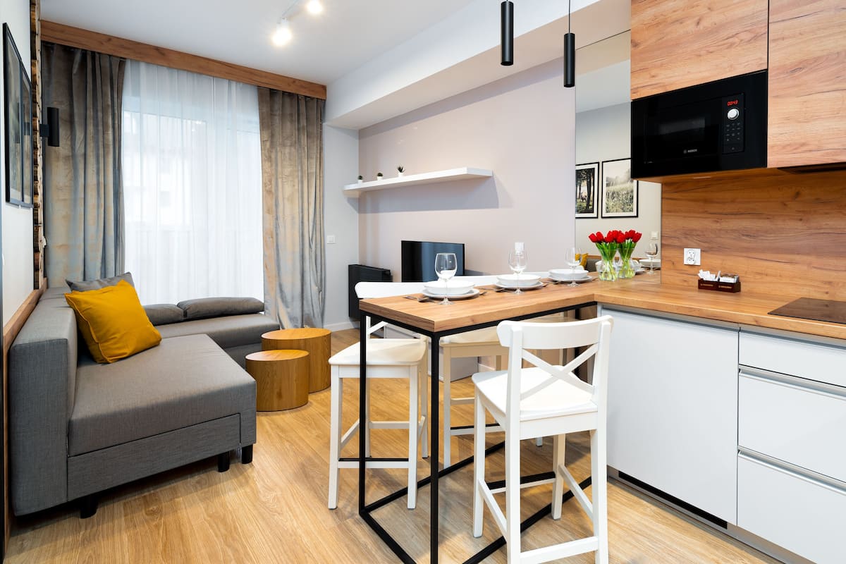 A modern kitchen with white cabinets, a wooden countertop, and a built-in microwave.