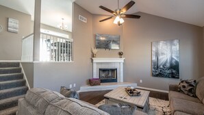 A living room with a fireplace, a ceiling fan, and a large painting on the wall. - Luxury Meets Convenience *** Four Beds, Three Full Baths*** (Smithville)